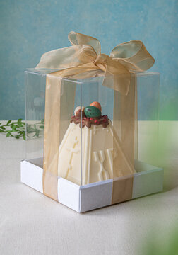 Tasty curd or souffle Easter cake with chocolate decor and eggs in transparent packaging