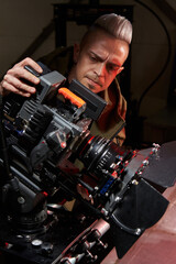 caucasian male videographer intensely seriously peers into the monitor of a professional movie camera on the set