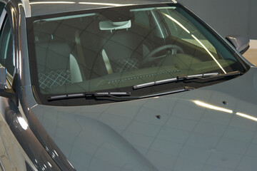 clean transparent windshield of a gray car. windshield wipers, front panel, steering wheel, seats are visible