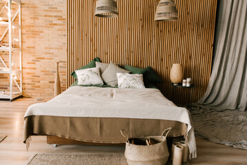 Modern boho bedroom interior with wooden slats, wicker lamps, emerald textiles