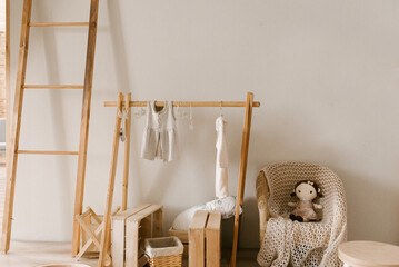 Fototapeta na wymiar Stylish Scandinavian-style children's room interior with wooden hanger and baby clothes