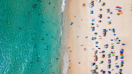 Fototapeta na wymiar Aerial top view Of people crowd relaxing on beach with colorful umbrellas in Phuket, Thailand, Aerial view of sandy beach with tourists swimming in beautiful clear sea water in Thailand.