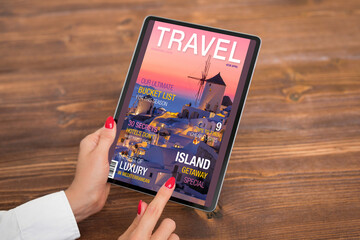 Woman reading travel magazine on tablet computer