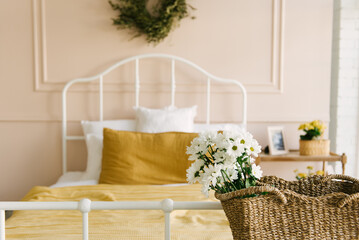 Beautiful stylish interior of a bright bedroom with a white bed by the window and textiles