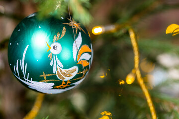 green glass ball decorated of cockerel image on christmas tree close up indoor