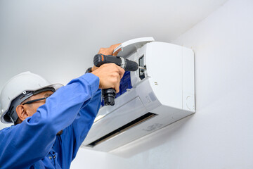 A male air conditioner technician or air conditioning installation. technician is about to repair...