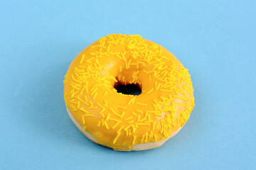 A yellow donut with yellow icing and sprinkles on it, copy space  