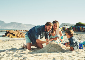 Sandcastle, parents and children at the beach with bonding, love and support. Baby, mom and dad together with kids playing in the sun with happiness and smile by the ocean and sea with family