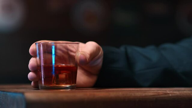 Brutal male hand mixing ice cubes in alcohol whiskey glass on table at bar nightclub closeup slowmo