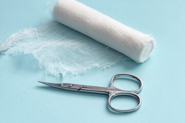 Medical gauze bandage and scissors on a blue background. Gauze and scissors close-up. First aid...