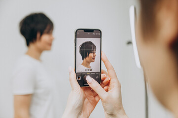 The hairdresser photographs his client in a new way. the hairdresser photographs the result for his...