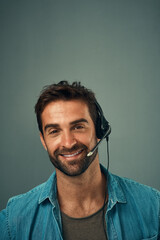 Happy man, call center and consultant with headphones on mockup space against grey studio background. Portrait of friendly male consulting agent with smile and headset in contact us for online advice