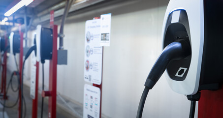 Electric car charging station for charge EV battery. Plug for electric vehicle. EV charger. Charging point at car parking lot of the mall. Clean and sustainable energy. Commercial EV charging point.