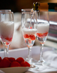 Pouring champagne into a glass with strawberries.
