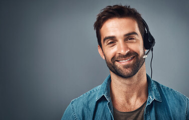 Happy man, call center and headphones for consulting on mockup space against a grey studio background. Portrait of friendly male consultant agent with smile and headset in contact us or online advice