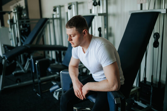 The Aftermath of Dedication A male gym goer finds tranquility and rest after a challenging training session. A tired guy seeks relaxation and relief from fatigue after a demanding workout at the gym.