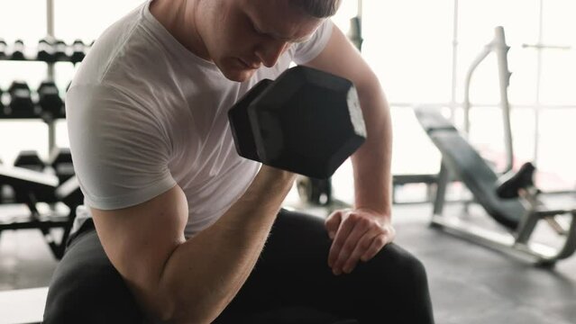A determined guy lifts weights during a high-intensity gym workout, aiming to improve his physical fitness. Active young man engaging in a challenging weightlifting routine, focusing on his fitness