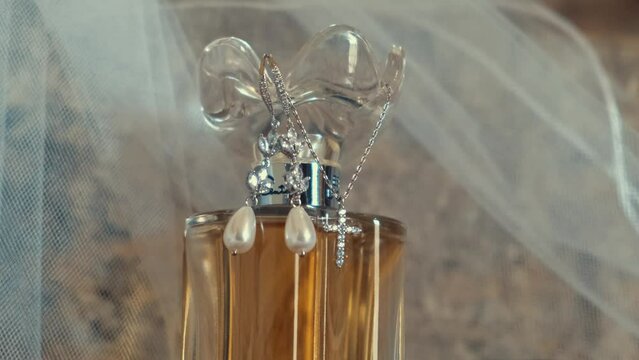 diamond and pearl bridal jewelry draped over a glass bottle of holy oil after the wedding
