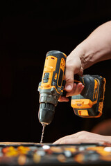 side view of a drill and an electric drill-driver with a replaceable battery held by a worker's hand