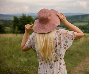 beautiful young woman in a hat and a dress with a bouquet of flowers in the field