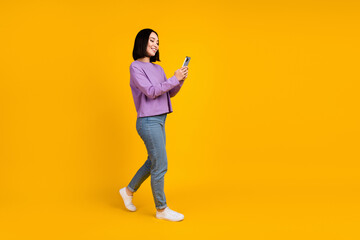 Fototapeta na wymiar Full body size photo of young chinese blogger girl hold phone walking recording video online popularity isolated on yellow color background