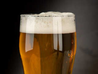A glass of cold beer on a dark background. Glass of beer close-up.