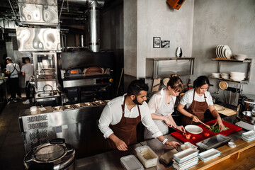 Top view of serious multinational chefs prepare healthy food in kitchen