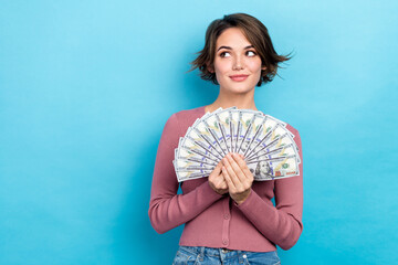 Photo of shiny dreamy lady wear pink cardigan holding money fan looking empty space isolated blue color background