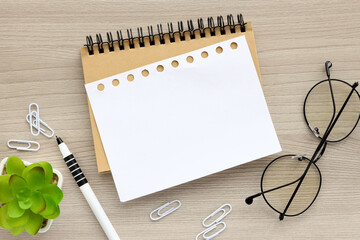 Top view of blank open notepad on wooden table background. Workplace for creative work of home...