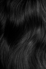Brunette or black hair. Female long dark hair in black. Beautifully laid curls. Closeup texture in a dark key. Hairdressing, hair care and coloring. Shading gray hair. Background with copy space.