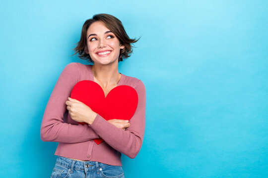 Photo of thoughtful sweet lady wear pink cardigan hugging red heart looking empty space isolated blue color background