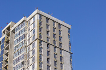 Modern high-rise buildings made of concrete and glass. Construction site. The final stage of construction. Against the background of the blue sky.