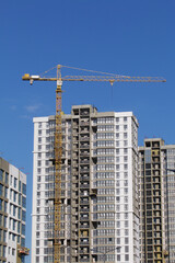 Fototapeta na wymiar Construction site. Reinforced concrete frames of multi-storey buildings and construction cranes. Against the background of the blue sky.