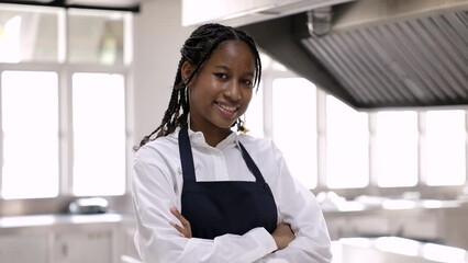Head shot portrait self-confident girl walking in cooking school with smile looking at camera, young afro hair African American chef student standing in kitchen, girl happy alternative career choice