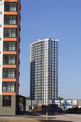 Modern high-rise buildings made of concrete and glass. Color design of facades. Construction site. The final stage of construction. Against the background of the blue sky.