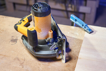 wooden workbench with clamped part and lying circular saw after working in wood shavings