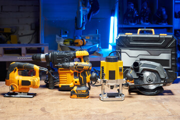 Fototapeta premium A set of tools and electrical devices is on the table. circular saw, screwdriver, perforator, drill, jigsaw, router in a carpentry workshop