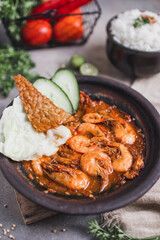 Udang sambal gami or spicy prawn is Traditional food from Indonesia. served on plate with a bowl of rice and vegetables. Isolated gray background