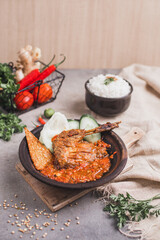 Bebek goreng sambal gami or spicy fried duck is Traditional food from Indonesia. served on plate with a bowl of rice and vegetables. Isolated gray background