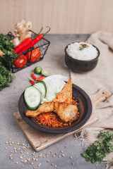 Ayam sambal gami or spicy fried chicken is Traditional food from Indonesia. served on plate with a bowl of rice and vegetables. Isolated gray background