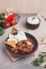 Iga sapi sambal gami or spicy beef ribs is Traditional food from Indonesia. served on plate with a bowl of rice and vegetables. Isolated gray background 