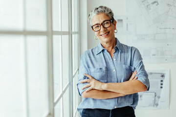Happy female architect standing in her office with crossed arms - Powered by Adobe
