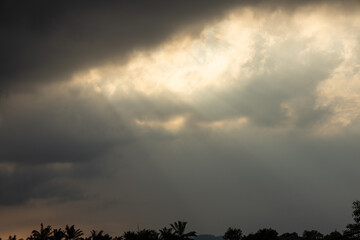 The sunlight can be seen radiating through the gaps in the dark clouds.