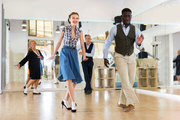 Man and woman performing jazz dance in dancing room
