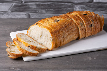 Bread with olives on a white cutting board on a gray table
