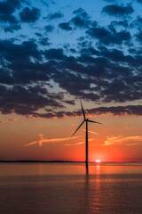 Obraz premium Wind turbine in the sea in the warm sunset light