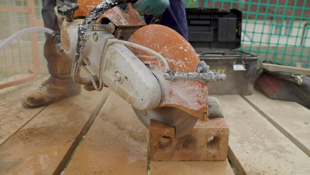 UK - bricklayer cuts off part of a brick with a circle cut off saw