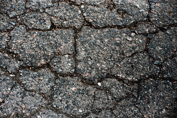 A network of black cracks on the asphalt surface. Road texture with weathered surface, showcasing the effects of time and wear