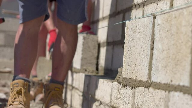 UK - a bricklayer adds mortar to a wall with his trowel