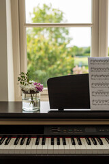 Electronic piano with notes and flowers in a vase